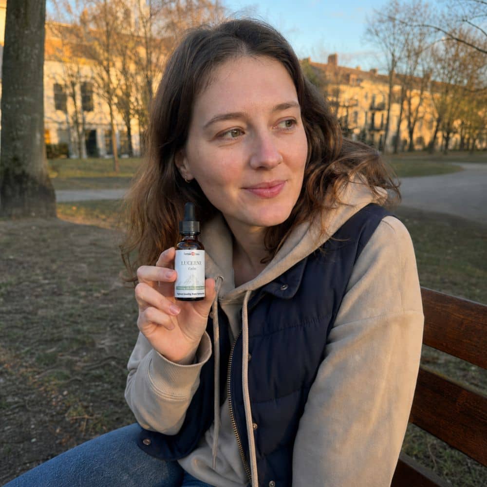Kvinde, der holder en flaske Lucerne CBD olie udendørs i en park